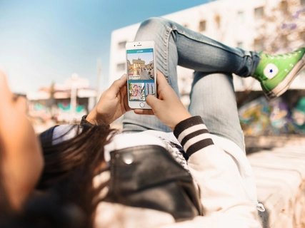 Young woman uses street art highlight of the ABOUT BERLIN app.