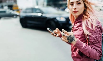 Junge Frau bewegt sich durch eine Stadt und hält ein Smartphone in der Hand
