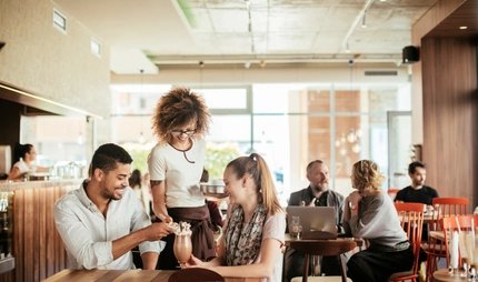 Eine Kellnerin bedient ein Paar im Café in Berlin